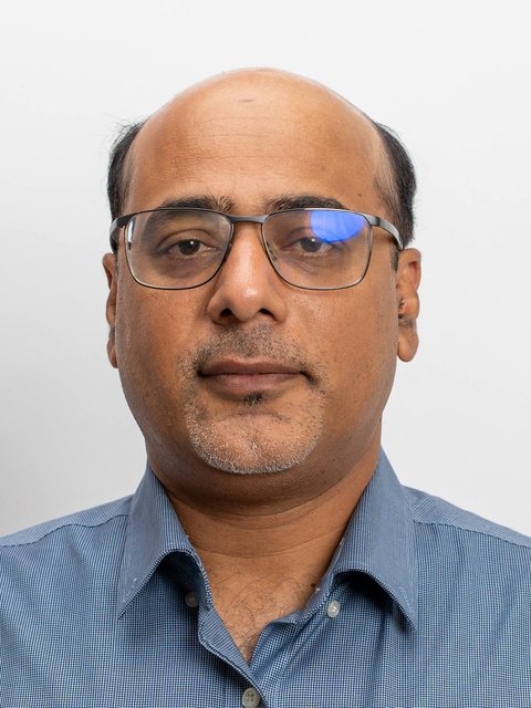 A man in front of a plain wall, looking at the camera
