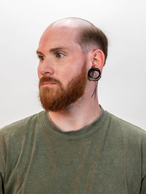 A man photographed half turned, against a plain wall